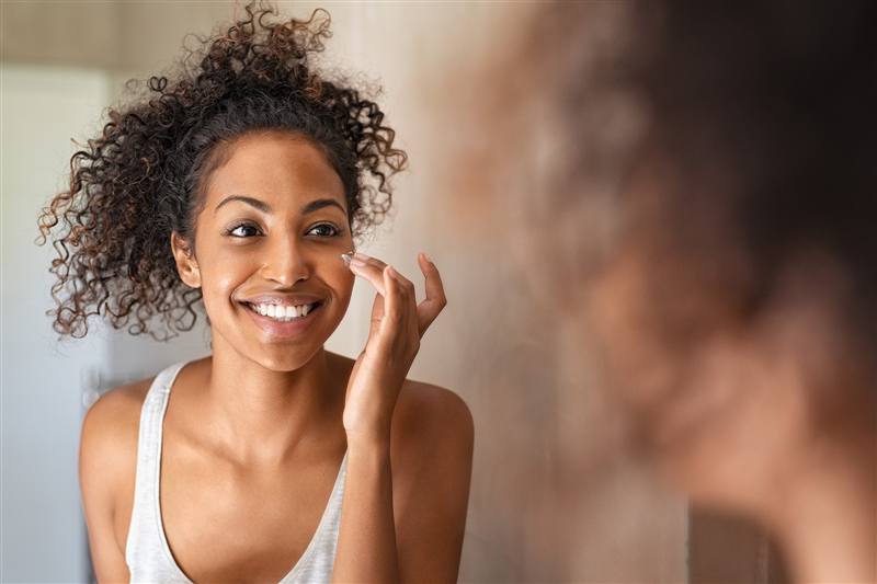A woman applying skincare serum to her face with her fingertips